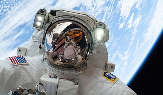 身穿太空服的太空人在太空中的照片，背景是地球和大气层